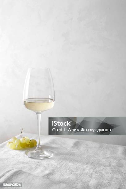 White Wine In A Glass And A Bunch Of Grapes On The Table Light Background Stock Photo - Download Image Now