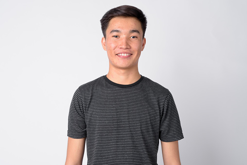 Studio shot of young handsome Asian man against white background
