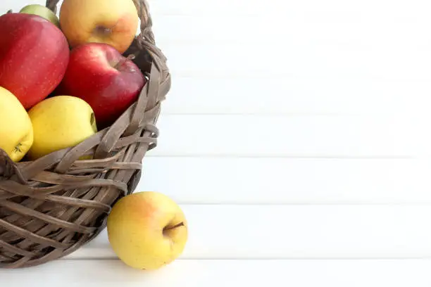 many multi-colored apples in a wicker basket on the table front view