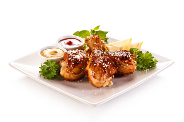 istock Roast chicken drumsticks with vegetables on white background 1186849652