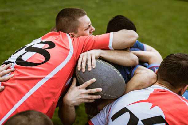 istock Determined rugby player trying to pass through his aggressive rivals on a match at playing field. 1186855413