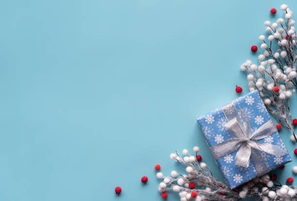 istock Merry Christmas gift box silver bow with red white branches winter holidays decorations festive blue background, happy 2020 new year handmade holiday present concept, flat lay, copy space top view 1186855625