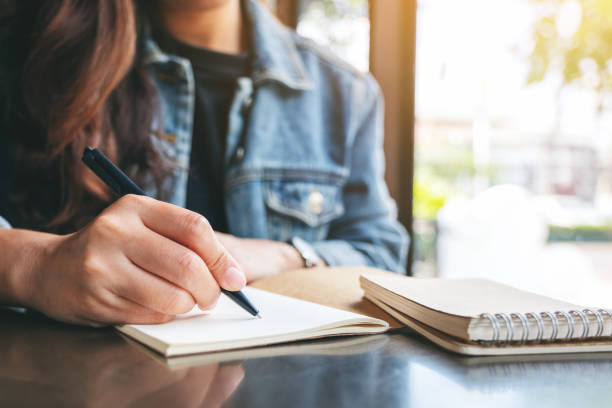 istock a woman writing on a blank notebook on the table 1186858731