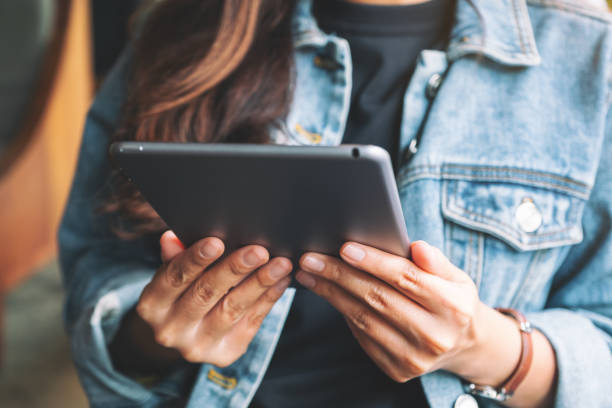 istock a woman holding and using tablet pc while sitting in cafe 1186859208