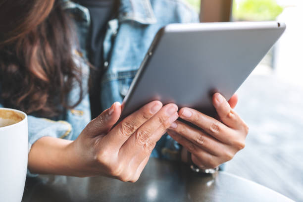 istock a woman holding and using tablet pc with coffee cup on the table 1186859906