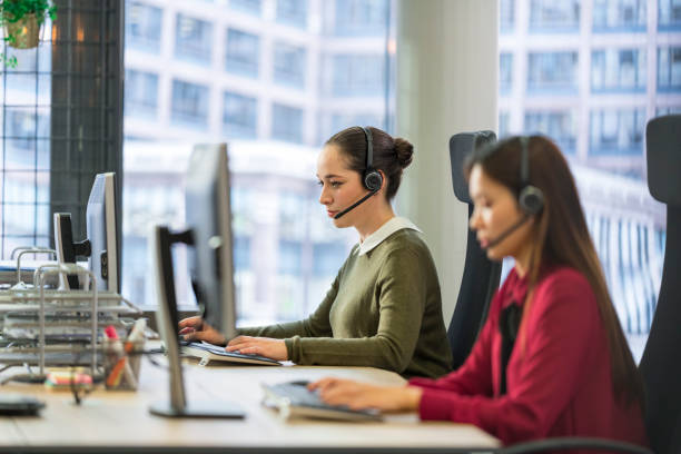 Customer service representative working in call centre Customer service representative wearing wireless headset working on desktop computer in call centre. olive green shirt stock pictures, royalty-free photos & images