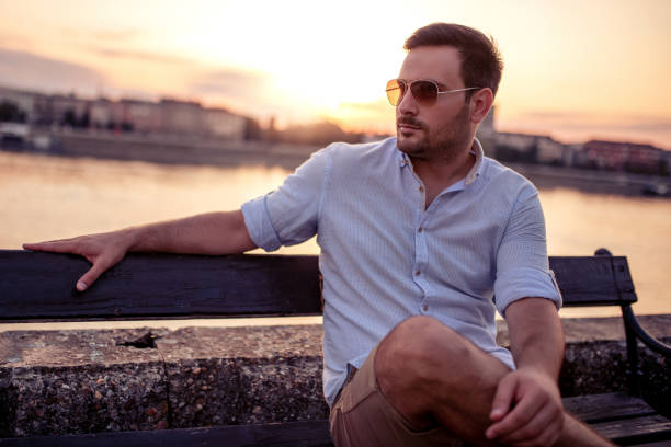istock Handsome man sitting on the bench by the river 1186863755