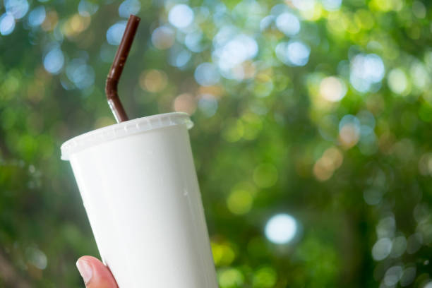 istock White paper cup with drinking straw in hand on nature background 1186863864