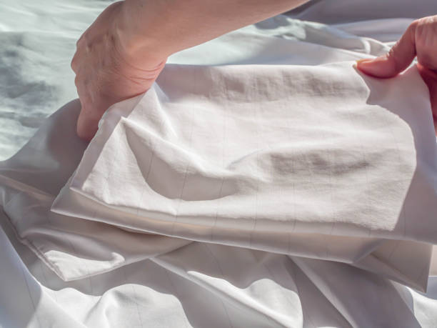 cubierta de almohada de ácaros de polvo con cremallera plegable de la mujer sobre la cubierta de la cama blanca arrugada en la cama en el dormitorio. - plegar fotografías e imágenes de stock