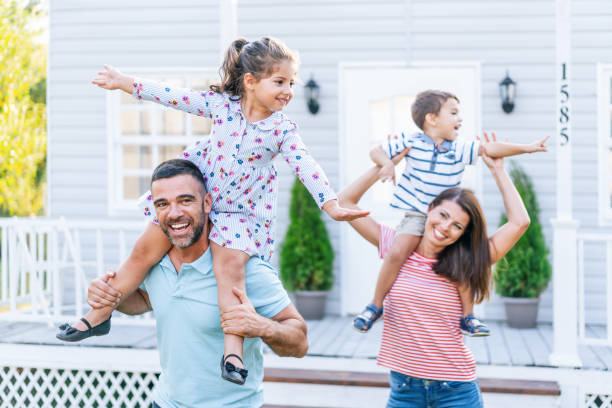 istock Parents having fun in front yard carrying children piggyback 1186864899