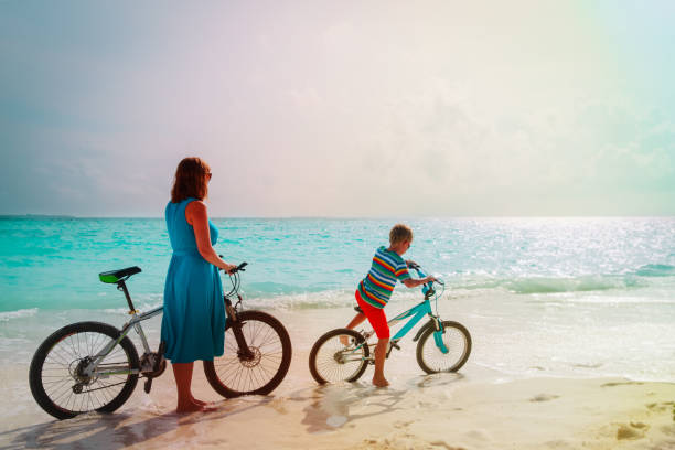 istock mother and son riding bikes on tropical beach 1186867081