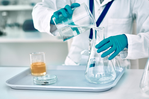 Cropped shot of an unrecognizable female scientist transferring a liquid from a beaker to a conical flask while working in a laboratory