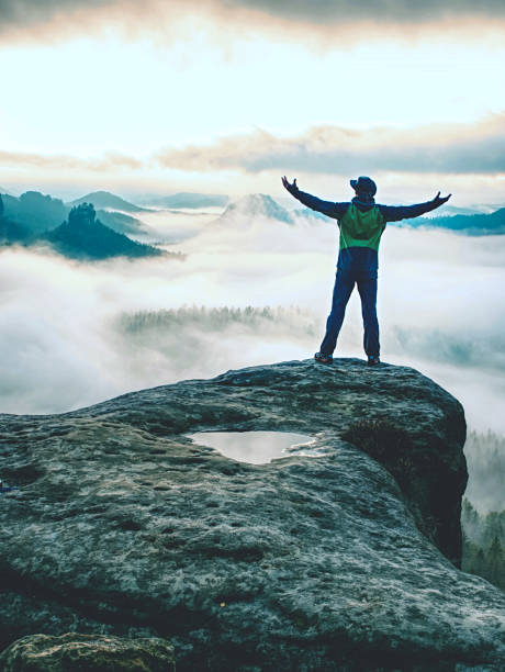 istock Men on mountain enjoy aerial view, arms raised over clouds 1186867646
