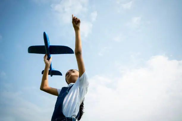 Photo of Asian little girl playing with airplane against the blue sky. Freedom open concept