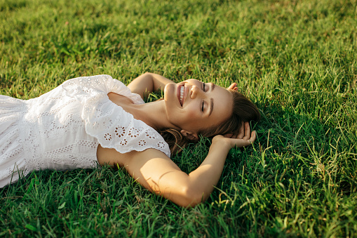 High Angle View Of Smiling Young Woman Lying Down On Grass