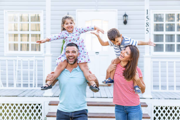 istock Parents having fun in front yard carrying children piggyback 1186877782