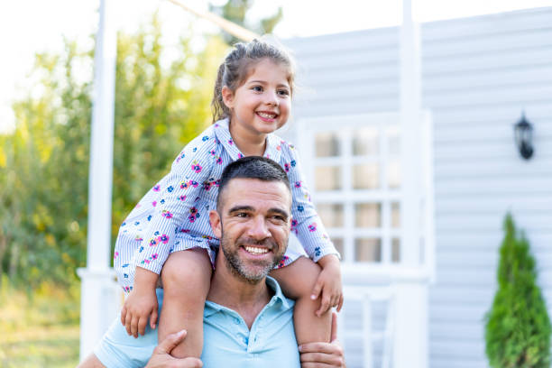 istock Father carrying his daughter on piggyback in front yard 1186877784