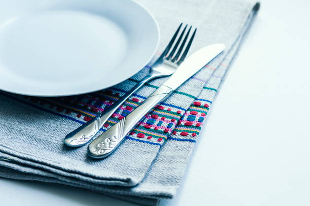 istock Table setting for dinner: a white plate, a fork, a knife on a woven cloth napkin with an embroidered pattern,  traditional handmade in Ukraine 1186881601