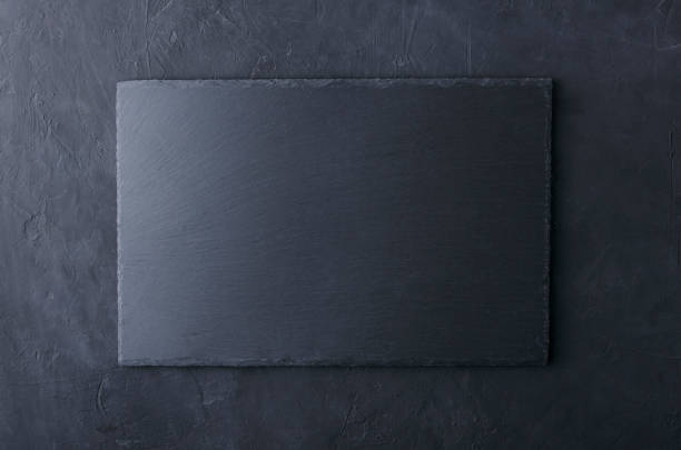 istock Top view of slate table mat on the black surface.Empty space for design 1186881644