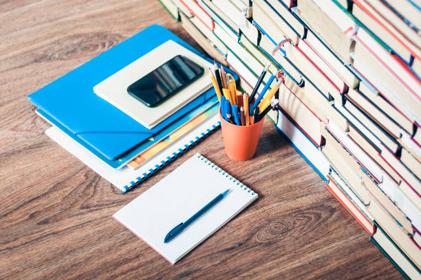 istock textbook, notebook, smartphone, pencils in holder, stack of old book education concept background, many books piles with copy space for text 1186884057