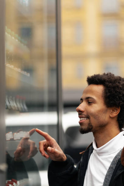 istock African man buys drink or sweets at vending machine outside 1186884256