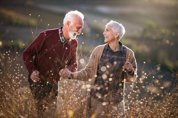 istock Cheerful mature couple talking while walking through tall grass in nature. 1186886826