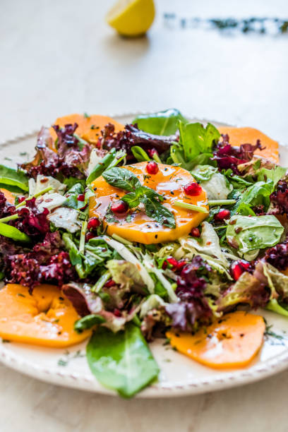 istock Persimmon Fruit Salad with Pomegranate, Lollo Rosso Lettuce, Rocket Arugula or Rucola and Mint Leaves. 1186890103