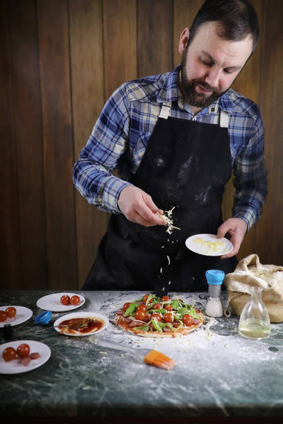 istock man preparing a pizza, knead the dough and puts ingredients 1186891466