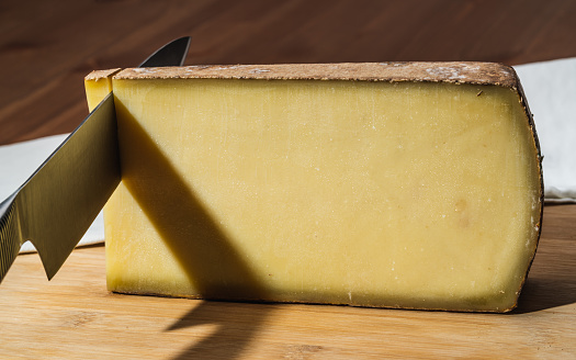 Knife cutting a piece of aged Comte a famous French cheese