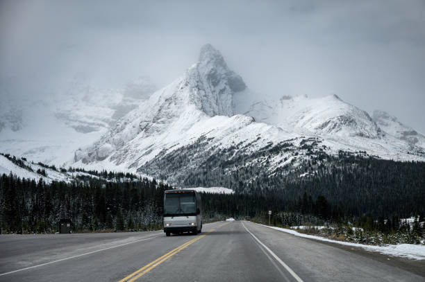 conduite d'autobus sur la route d'asphalte avec le grand fond de montagne de neige - asphalt two lane highway natural phenomenon fog photos et images de collection