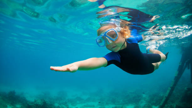 enfant dans la plongée sous-marine de masque de tuba dans la lagune bleue de mer - exercising wetsuit people expressing positivity photos et images de collection