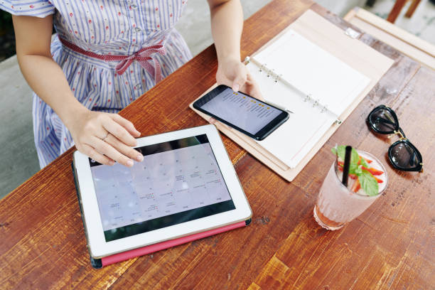 Hands of young woman checking calendar on her tablet computer and reading travel packing checklist