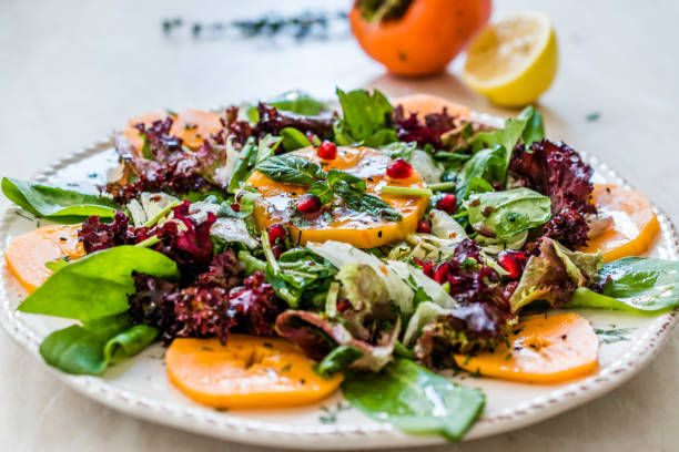 istock Persimmon Fruit Salad with Pomegranate, Lollo Rosso Lettuce, Rocket Arugula or Rucola and Mint Leaves. 1186895085