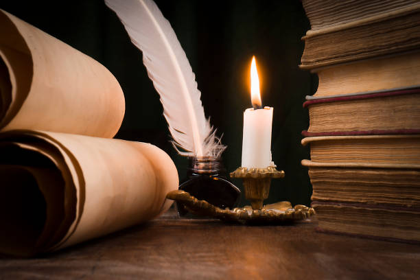 istock Scrolls of parchment, a stack of books, and a lit candle 1186897449