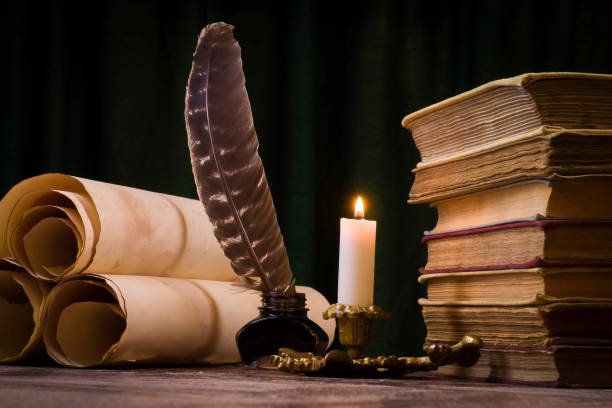 istock Scrolls of parchment, a stack of books, and a lit candle 1186897489