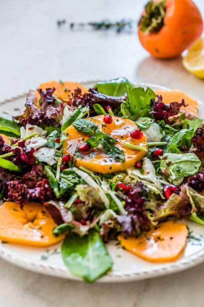 istock Persimmon Fruit Salad with Pomegranate, Lollo Rosso Lettuce, Rocket Arugula or Rucola and Mint Leaves. 1186898157