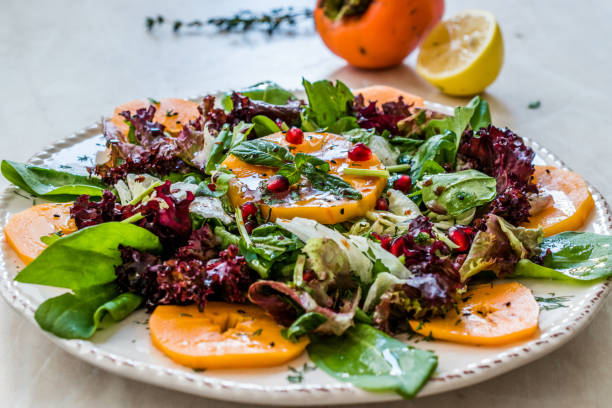 istock Persimmon Fruit Salad with Pomegranate, Lollo Rosso Lettuce, Rocket Arugula or Rucola and Mint Leaves. 1186899402