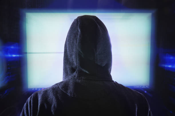 istock Anonymous hacker is looking at computer monitor. View from behin 1186902118