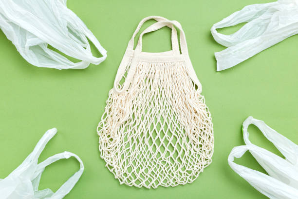 istock Alternative reusable mesh bag versus plastic on green background. Reusable concept. Flat lay 1186904349