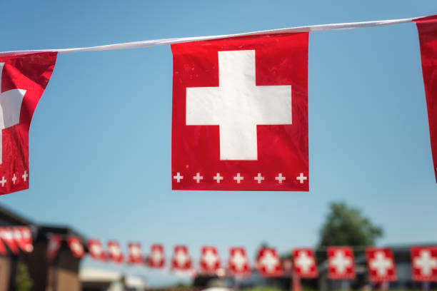 flag of Switzerland fluttering in the blue sky with cumulus clouds