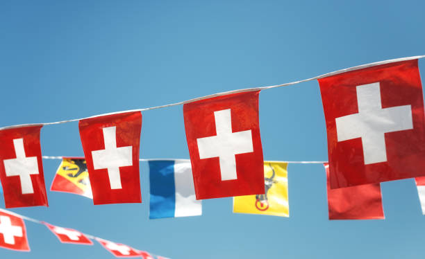 Flags fluttering in the wind against a blue sky background (from left to right: Ermatingen municipal flag, Swiss flag, Canton of Thurgau, Triboltingen municipal flag), Ermatingen, Canton of Thurgau, Switzerland