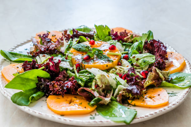istock Persimmon Fruit Salad with Pomegranate, Lollo Rosso Lettuce, Rocket Arugula or Rucola and Mint Leaves. 1186906009