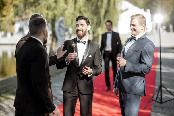 Men as a famous movie actors gathering together and greeting each other on the red carpet at the awards ceremony outdoors
