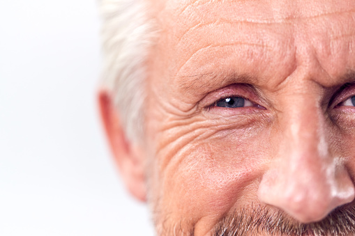 Studio Shot Of Mature Man Cropped On Eyes Against White Background Smiling At Camera