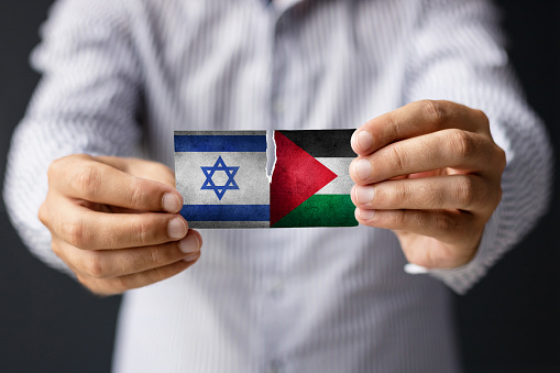 Israel vs Palestine. Close-up of man holding Israeli and Palestine flag.