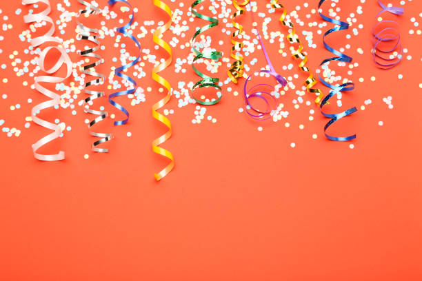 istock Colorful ribbons with confetti on red background 1186909495