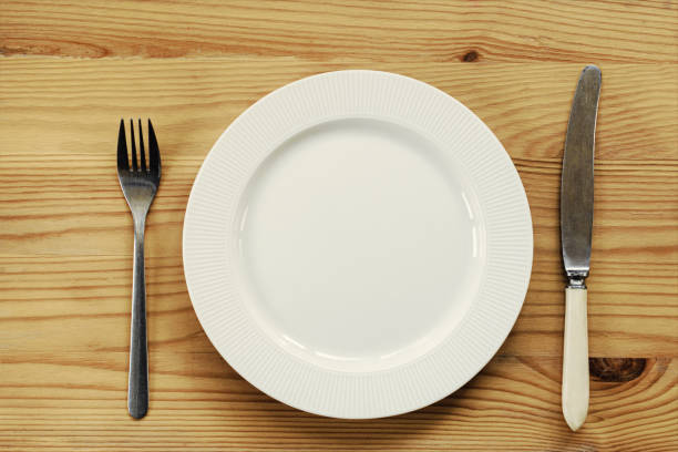 istock White plate and knife with a fork are served on a wooden table. view from above. 1186909533
