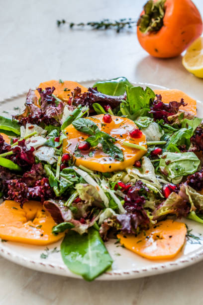 istock Persimmon Fruit Salad with Pomegranate, Lollo Rosso Lettuce, Rocket Arugula or Rucola and Mint Leaves. 1186910597