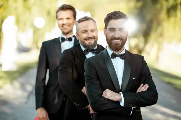 Group portrait of an elegant men as a famous movie actors standing on the red carpet during awards ceremony outdoors