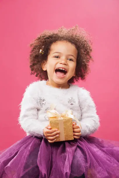 Photo of Happy little girl holding a shiny gift box